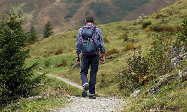 um homem caminando pela mata com mochila nas costas