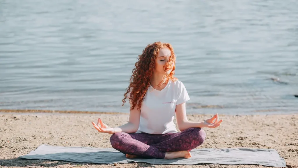 uma mulher meditando na praia