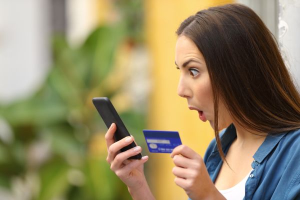 Surpreenda da Mastercard. Tutorial Completo Aqui mulher olhando o celular e o cartão com olhar de surpresa