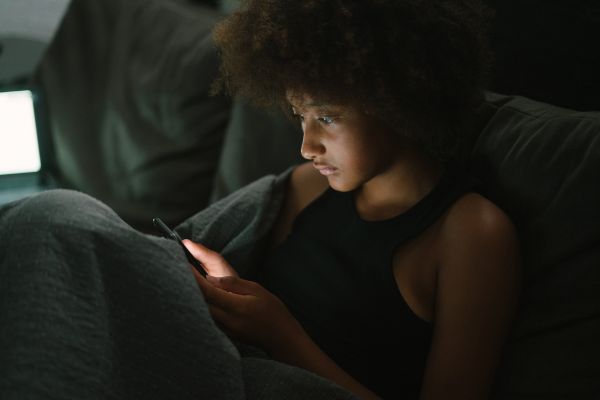 causas da solidão uma garota sentada no sofá olhando celular