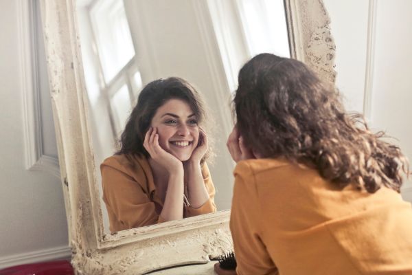 aceitação pessoal mulher olhando pro espelho e sorrindo