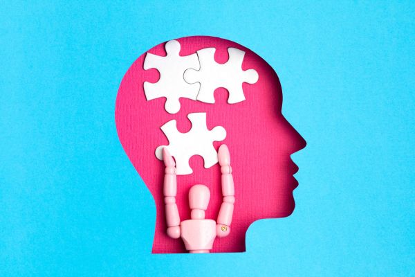 saúde mental desenho de uma cabeça com boneco e 3 peças de quebra cabeça com fundo azul