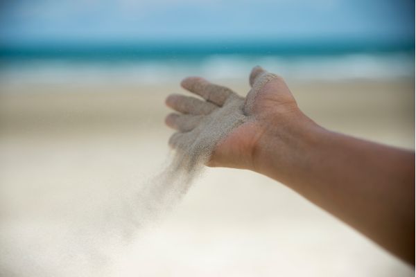 7 leis espirituais deepak chopra uma mão pegando areia e soltando