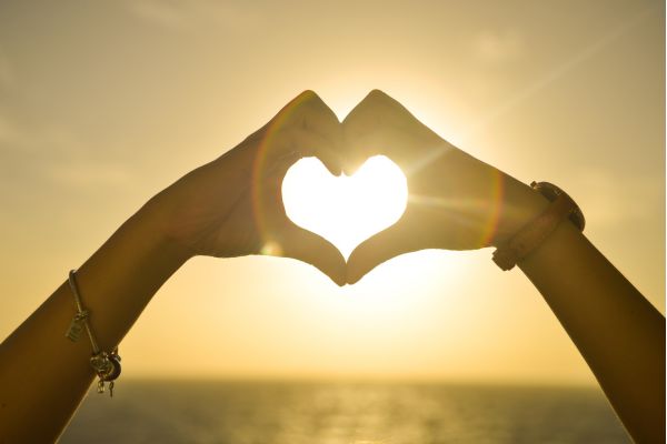amor um braço fazendo sinal do coração ne frente ao por do sol