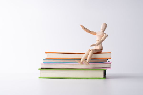 autoconhecimento boneco em cima de 4 livros