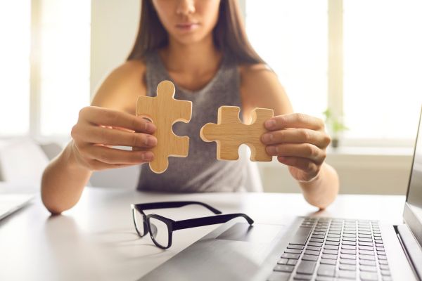 tomada de decisão mulher sentada, óculos, computador e dois quebra cabeças
