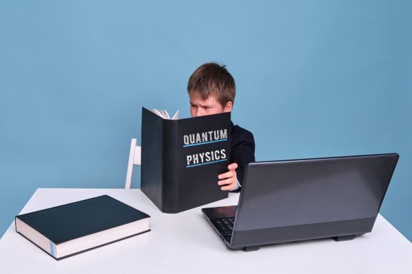 garoto com computador lendo um livro de física quantica