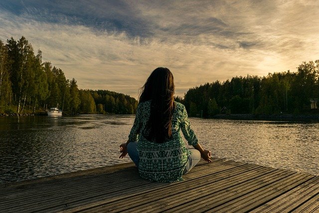 mulher sentada de frente para o lago olhando o céu azl