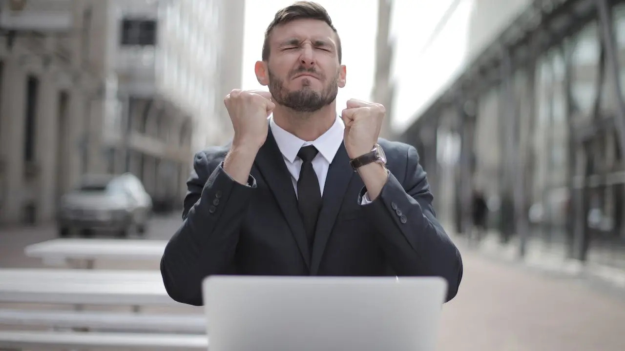 um homem de terno com braço pro alto e olho fechado