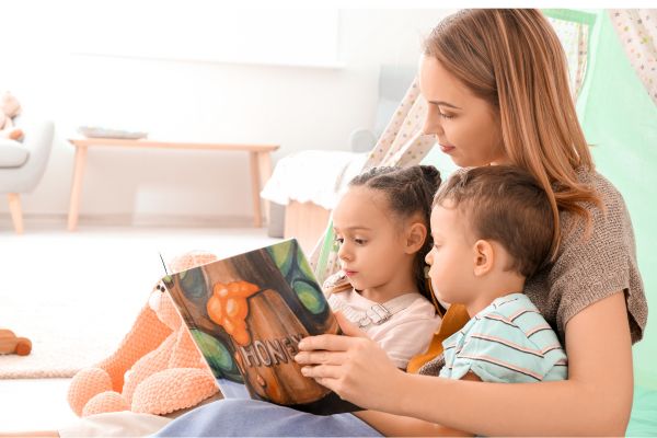 Família Narcisista: Como Filhos Adultos Podem Romper o Ciclo e Se Curar uma mão com livro aberto mostrando para duas crianças. um menino e uma menina.
