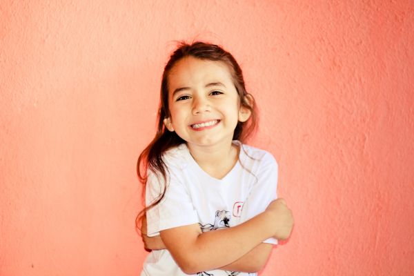 uma criança se abraçando e sorrindo com fundo com de abóbora