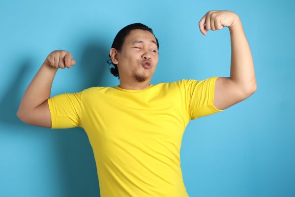 codependencia e narcisistas homem mostrando braço forte e camisa amarelo com fundo azul
