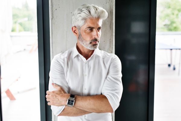 Como Conquistar Homens Mais Velhos: 10 Passos para Uma Conexão Verdadeira homem de barba e cabelo grisalho com braços fechados e camisa branca