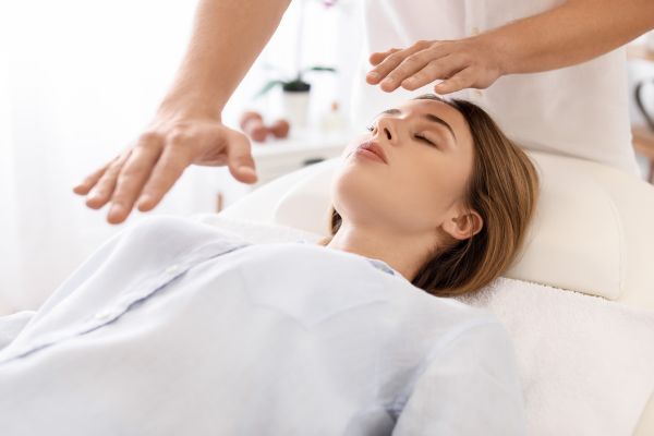 mulher deitada com terapeuta com mão na sua testa e barriga