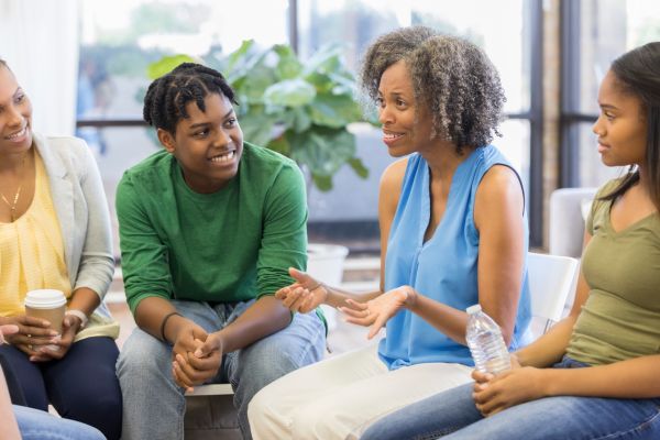 saúde mental no trabalho 4 pessoas sorrrindo sentadas