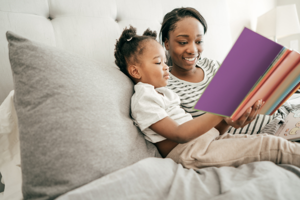 Como Ler Livros de Forma Eficaz: Método pra Otimizar sua Leitura uma mãe lendo um livro ao lado de uma criança