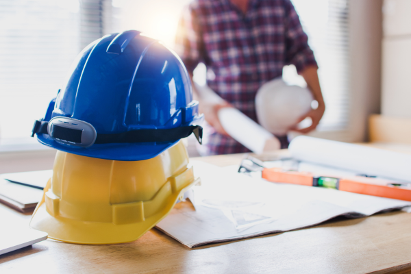 um homem e dois capacetes de segurança no trabalho