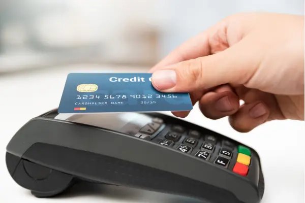Milhas do Cartão de Crédito: Como acumular pontos Fácil e Rápido uma mão segurando cartãod e credito e uma maquina de cartão