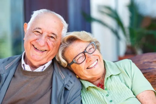 Relacionamentos na Terceira Idade: Desafios, Benefícios e Dicas para uma Vida Social Saudável casal de velhinhos sorrindo com a velhinha na cabeça no ombro do velhinho