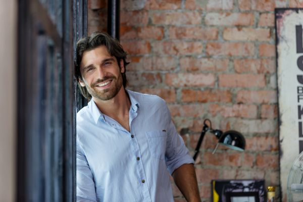 como ativar o instinto primitivo feminino Um homem encostado na parede sorrindo