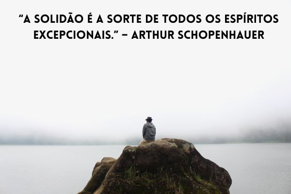 uma pessoa de chapéu sentada na pedra olhando um lago