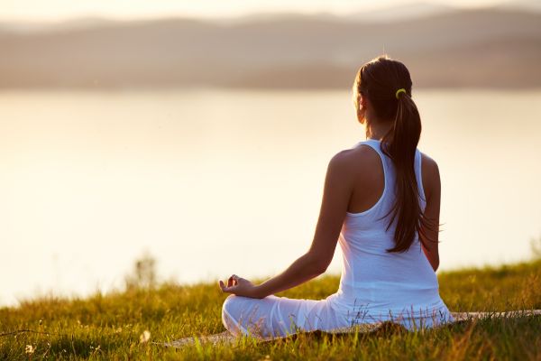 meditação mulher sentada meditando em frente ao lago
