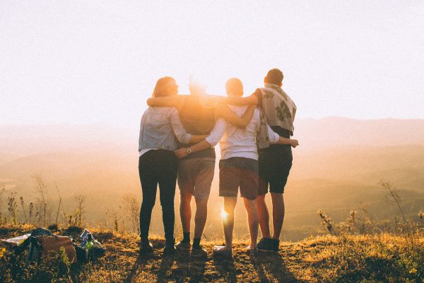 poder das conexões quatro pessoas abraçadas olhando o sol